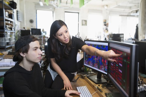 Man and woman examining circuits on computer monitors
