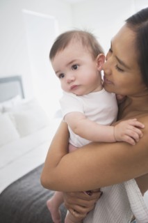 Mother hugging baby son in bedroom