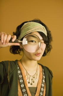 Asian woman looking through magnifying glass