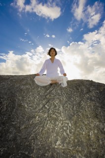 Asian woman meditating on rock