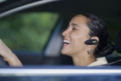Hispanic woman driving with hands-free cell phone device