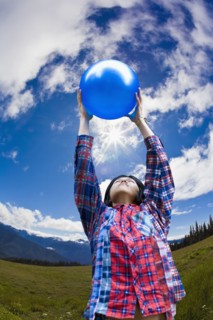 Asian man lifting ball in remote field