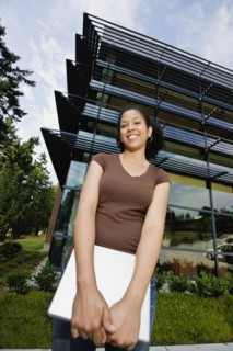 Mixed race woman holding laptop on campus outdoors