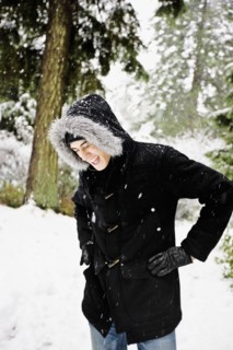 Mixed race man in hooded coat outdoors in snowfall