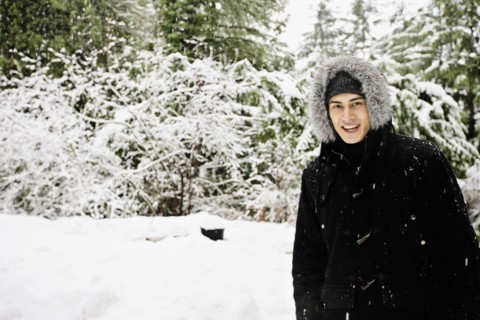 Mixed race man in hooded coat outdoors in snowfall