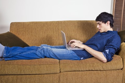 Mixed race man typing on laptop on sofa