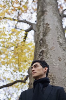 Pensive mixed race man standing under autumn tree