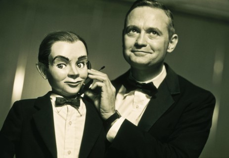 Performer holding cell phone to ventriloquist dummy