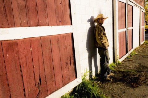 Caucasian farmer leaning on barn wall