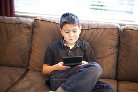 Mixed race teenage boy playing video games on sofa