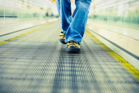 Legs of Japanese woman wearing jeans walking on moving walkway