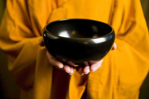 Monk in orange robe holding black bowl