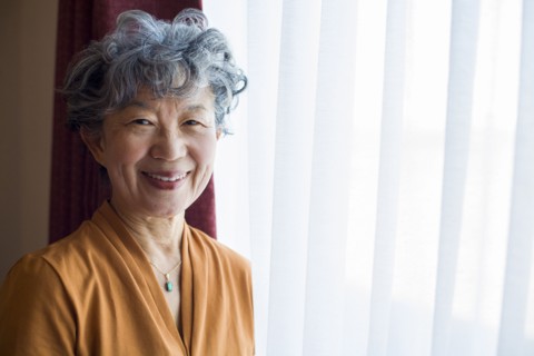 Smiling Japanese woman standing at window