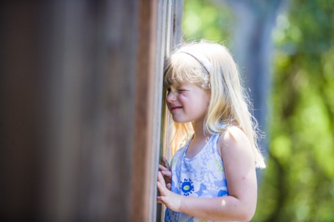 Curious Caucasian girl peeking through wooden fence