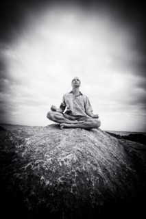 Caucasian man meditating on rocks at ocean