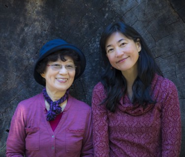 Older Japanese mother and daughter posing at tree slice