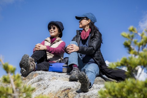Older Japanese mother and daughter sitting on rock