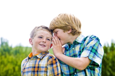 Caucasian boy whispering to brother