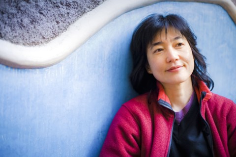 Pensive Japanese woman leaning on wall