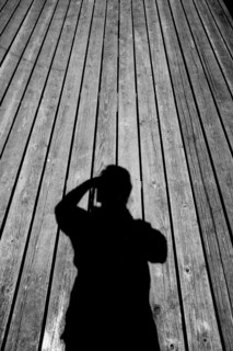 Shadow of Caucasian man with camera on wooden floor
