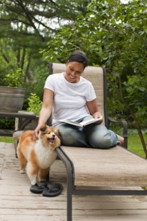 African American woman reading book and petting dog