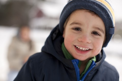 Mixed race smiling boy outdoors in coat and cap