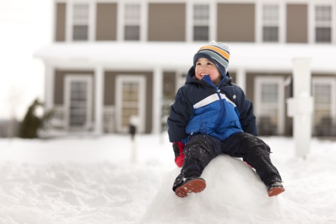Mixed race boy sitting on large snowball