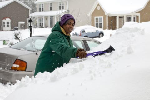 African American woman scraping snow from windshield