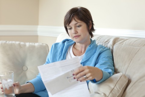 Caucasian woman on sofa reviewing bills