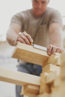 Caucasian construction worker marking wood planks