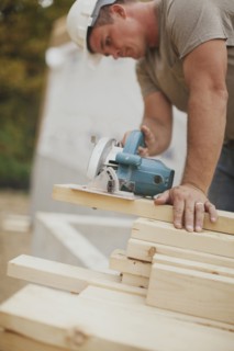 Caucasian construction worker sawing wood planks