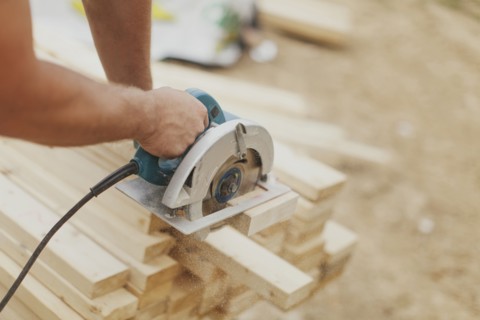 Caucasian construction worker sawing wood planks
