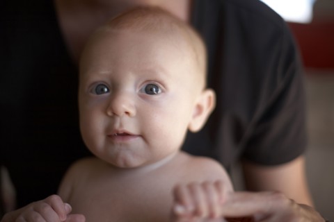 Caucasian mother holding baby's hands
