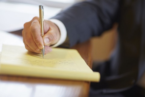 Mixed race businessman writing on notepad at desk