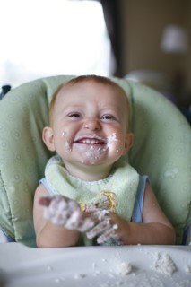 Caucasian baby eating cake in high chair