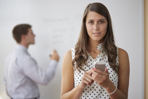 Mixed race businesswoman using cell phone in office