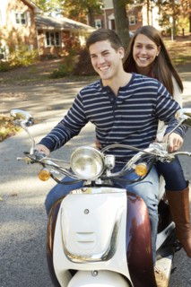 Couple riding scooter in suburban neighborhood