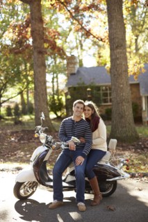 Couple sitting on scooter in suburban neighborhood