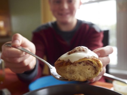 Caucasian boy showing cinnamon bun