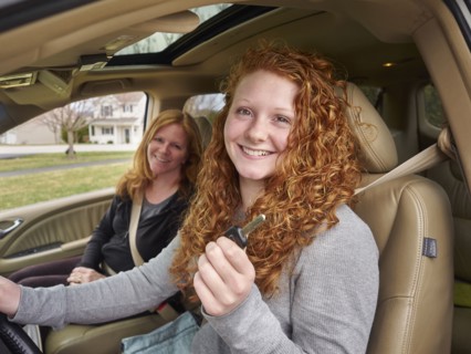 Caucasian teenage girl showing key with mother in car