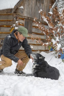 Mixed race man petting dog in snow
