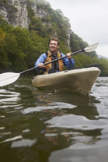Caucasian man paddling kayak on remote river