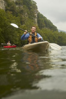 Caucasian man paddling kayak on remote river