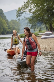 Women pulling kayaks in remote river