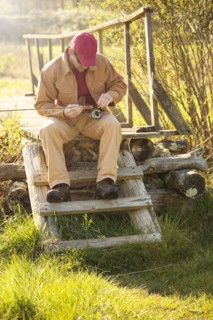 Caucasian man loading fishing pole on steps