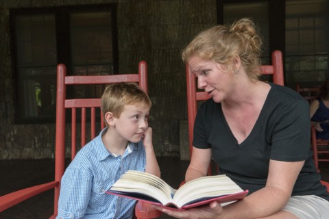 Caucasian mother and son reading on patio