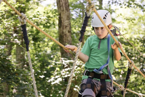 Caucasian boy balancing on rope bridge