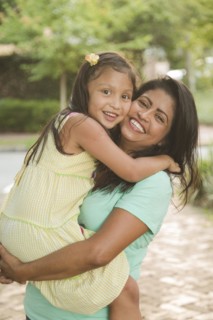 Hispanic mother carrying and hugging daughter