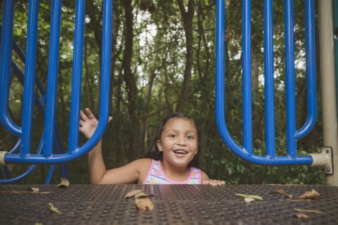 Smiling Hispanic girl reaching on playground