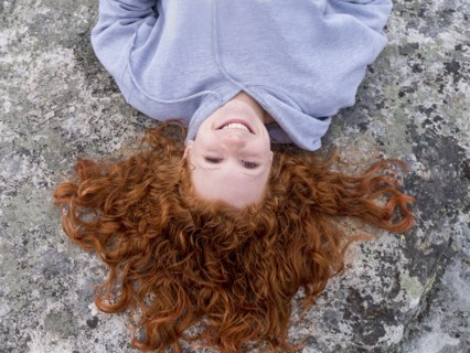 Portrait of smiling Caucasian girl laying on rock